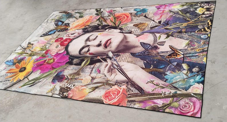 May include: A rectangular art print featuring a woman's portrait surrounded by colorful flowers and butterflies. The woman is holding paintbrushes. The artwork has a collage style with newspaper clippings in the background.