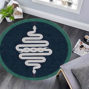 Può includere: Un tappeto rotondo con sfondo blu scuro e bordo verde. Il tappeto presenta un disegno di serpente bianco con lingua rossa.