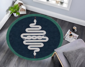 May include: A round rug with a dark blue background and a green border. The rug features a white snake design with a red tongue.