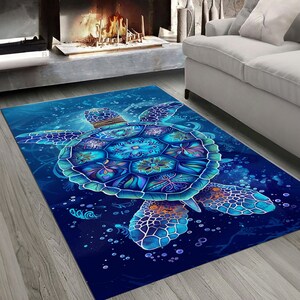 Op de afbeelding: Een blauw en paars gestreept tapijt met een groot zeeschildpad ontwerp. De schildpad heeft een gedetailleerd mandala-patroon op zijn schild en is omringd door bubbels.