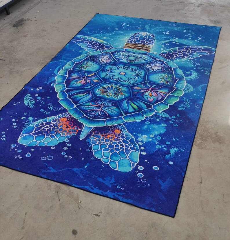 Op de afbeelding: Een blauwe en turquoise zeeschildpad met ingewikkelde patronen op zijn schild, zwemmend in een donkerblauwe oceaan met witte bubbels. Het schild van de schildpad is versierd met bloem- en geometrische patronen.