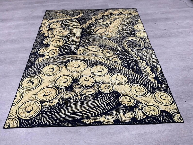 K&ouml;nnte beinhalten: Eine schwarze und goldene Wandteppich mit einer detaillierten Illustration eines Kraken mit ausgebreiteten Tentakeln. Der Krake ist in einem Vintage-Stil mit komplizierten Linien und Mustern dargestellt.