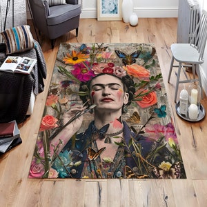May include: A rectangular area rug featuring a portrait of Frida Kahlo surrounded by colorful flowers and butterflies. The rug has a vintage newspaper background with the words "Spring Strange History" visible. The color palette includes pink, orange, blue, and green.
