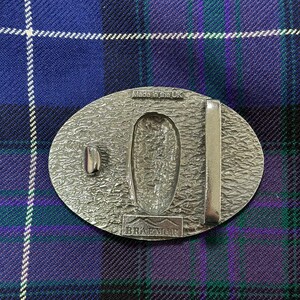 May include: Silver oval belt buckle with a textured surface and the words "Made in the UK" and "Braemar" engraved on it.