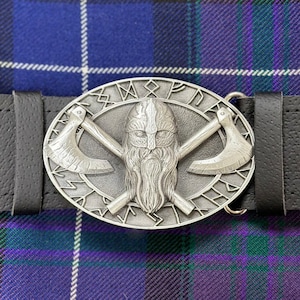 May include: A silver belt buckle with a Viking warrior design. The buckle features a bearded warrior with crossed axes and runes around the edge.