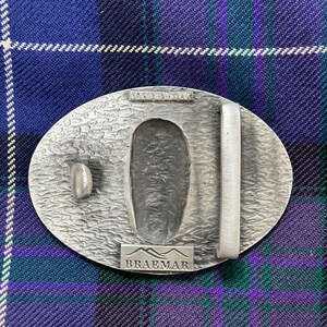 May include: A silver-toned metal belt buckle with a textured surface. The buckle features the words "Made in the UK" and "Braemar" in raised lettering.