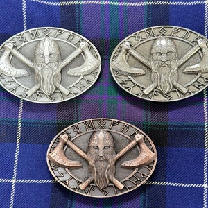 May include: Three silver and bronze Viking-themed belt buckles with a bearded warrior's face, crossed axes, and runes around the edge.