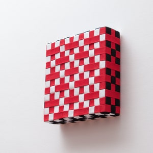 May include: A woven wall hanging with a checkered pattern in red, white, and black.