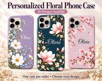May include: Three personalized phone cases featuring floral designs and the name Olivia. The left case is lavender with white and blue flowers. The center case is dark teal with pink magnolia blossoms. The right case is light pink with cherry blossoms.