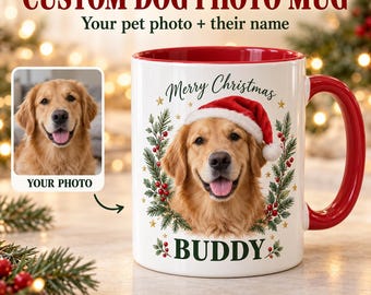 May include: A white ceramic mug with a red interior and handle, featuring a custom graphic of a golden retriever wearing a Santa hat, surrounded by a wreath of pine branches and red berries, with the text Merry Christmas and BUDDY.