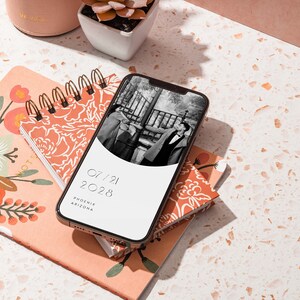 Op de afbeelding: Een smartphone die een save the date voor een bruiloft laat zien met een zwart-witfoto van een stel, de datum 07/21/2028 en de locatie Phoenix, Arizona.