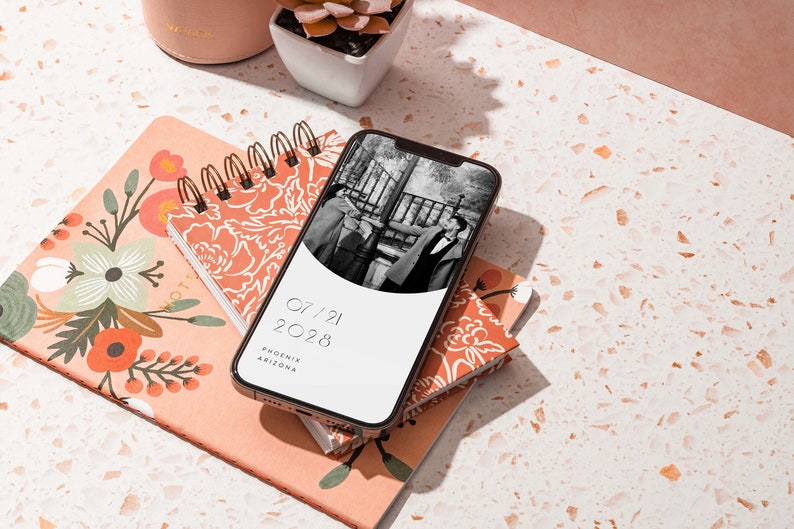 Op de afbeelding: Een smartphone die een save the date voor een bruiloft laat zien met een zwart-witfoto van een stel, de datum 07/21/2028 en de locatie Phoenix, Arizona.