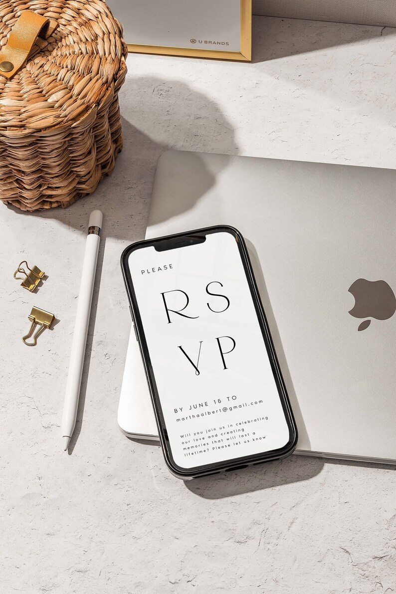 Op de afbeelding: Een zwarte smartphone met een wit scherm waarop een RSVP-verzoek wordt weergegeven. De tekst op het scherm luidt "PLEASE RSVP BY JUNE 16 TO marthaalbert@gmail.com Will you join us in celebrating our love and creating memories that will last a lifetime? Please let us know."
