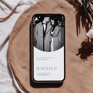 Op de afbeelding: Een smartphone-scherm toont een huwelijksuitnodiging met een zwart-witfoto van een stel op de achtergrond. De tekst luidt "Ter gelegenheid van het huwelijk van Martha & Albert".