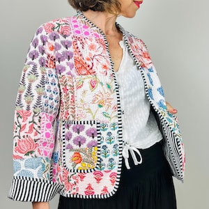 Pu&ograve; includere: Una giacca trapuntata patchwork colorata con stampa floreale. La giacca ha un colletto alla coreana, maniche lunghe e una cravatta in vita.
