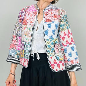 Pu&ograve; includere: Una giacca trapuntata bianca con una stampa floreale colorata. La giacca ha un colletto alla coreana, maniche lunghe e due tasche a toppa. La giacca &egrave; realizzata in cotone ed &egrave; foderata con un tessuto morbido.
