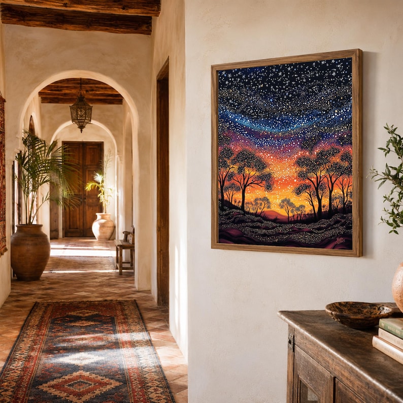 May include: A square framed painting hanging on a wall, depicting a landscape at twilight with silhouettes of trees against a vibrant orange and yellow horizon that transitions into a deep blue night sky filled with numerous white stars.