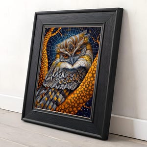 Op de afbeelding: Een ingelijste kunstdruk met een gedetailleerde illustratie van een uil. De uil heeft ingewikkelde patronen in bruin, goud en wit, met doordringende oranje ogen. Het kunstwerk is geplaatst tegen een sterrenhemel en ingelijst in een zwart houten frame.