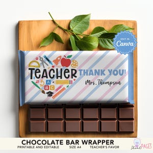 Pode incluir: Uma barra de chocolate com uma embalagem que diz "Teacher Thank You!" com gráficos escolares. A embalagem tem um design listrado azul, rosa e branco. A barra de chocolate está em uma tábua de madeira com folhas verdes.