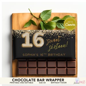 Peut inclure: Une barre de chocolat enveloppée dans du papier noir avec du texte et des accents dorés. L'emballage indique "16 sweet sixteen!" et "Sophia's 16th Birthday." La barre est posée sur une planche de bois avec des feuilles vertes.
