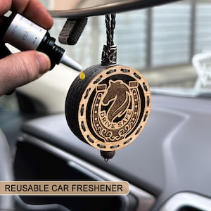 May include: A circular wooden car air freshener featuring a horse head and horseshoe design, with the words "DRIVE SAFE". A small bottle is used to apply scent. The text "REUSABLE CAR FRESHENER" is at the bottom of the image.