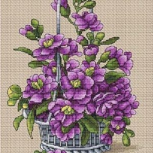 May include: Cross-stitch design of a basket overflowing with purple flowers and green leaves. The basket has a silver handle and is filled with detailed stitching. The background is a beige fabric.