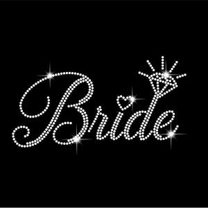 May include: A black background with the word "Bride" spelled out in white rhinestones. The letter "B" has a large, looping design. The letter "i" is topped with a heart. The letter "e" is topped with a diamond ring design.