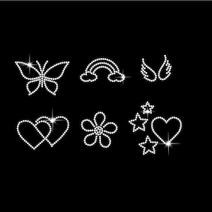 May include: A collection of rhinestone designs on a black background. The designs include a butterfly, rainbow, angel wings, two hearts, a flower, stars, and a heart. Each design is made of small, sparkling rhinestones.