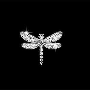 Könnte beinhalten: Ein funkelndes, weißes Libellen-Design auf schwarzem Hintergrund. Die Libelle besteht aus zahlreichen kleinen, runden, weißen Edelsteinen, die einen schimmernden Effekt erzeugen. Flügel und Körper sind mit den Edelsteinen detailliert, das Design ist zentriert.