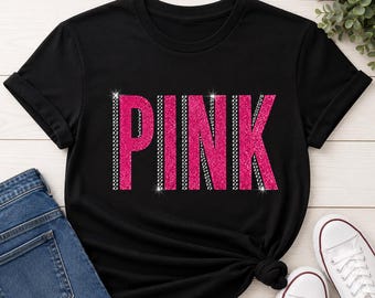 May include: Black t-shirt with the word "PINK" in large, sparkly pink letters. The letters are outlined with a silver, gem-like border. The shirt is paired with blue jeans and white sneakers.