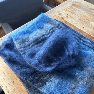 May include: A soft, blue and grey knitted scarf with a fuzzy texture.