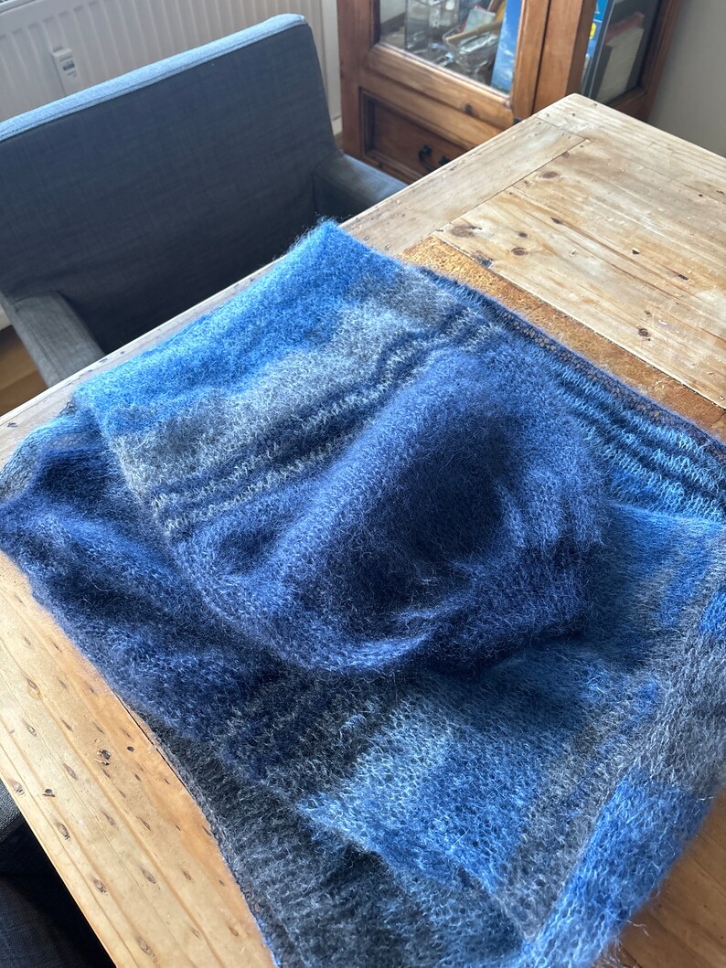 May include: A soft, blue and grey knitted scarf with a fuzzy texture.