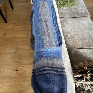 May include: A blue and grey striped knitted throw blanket with a fluffy texture.