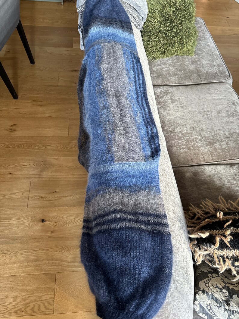 May include: A blue and grey striped knitted throw blanket with a fluffy texture.