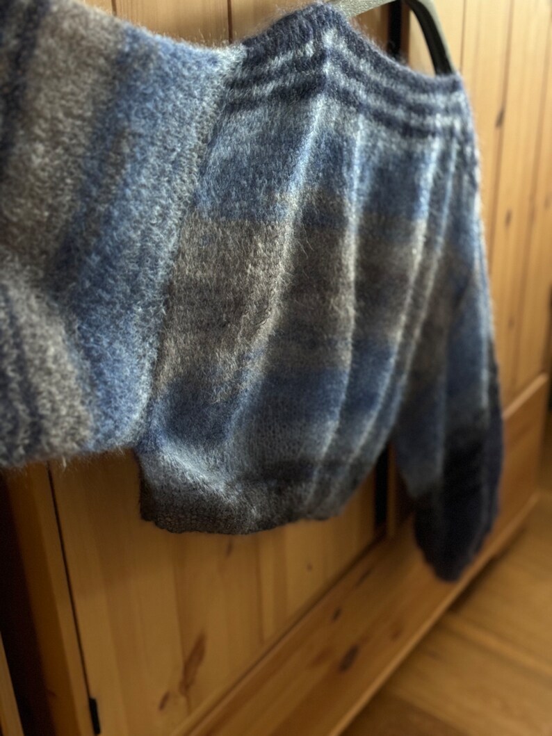 May include: A blue and grey fuzzy knit sweater with a loose fit and long sleeves.