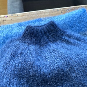 May include: A soft, blue and dark blue fuzzy fabric with a textured, fluffy surface.