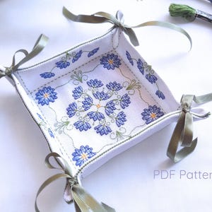 May include: Square white fabric tray with blue floral embroidery and green trim. The tray has olive green satin ribbon ties at each corner. The text "PDF Pattern" is visible in the lower right corner.
