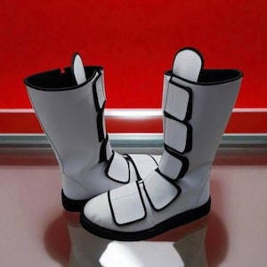 May include: A pair of white boots with black trim and accents. The boots have a tall shaft, a rounded toe, and multiple adjustable straps. The boots are set against a red and white background.