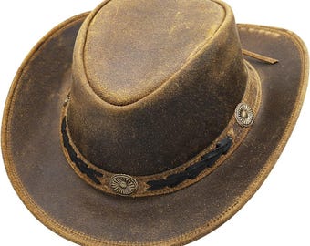 May include: A distressed brown leather cowboy hat with a rounded crown and wide brim. The hat features a decorative band with black stitching and two metal conchos. A leather strap is attached to the brim.
