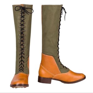 Könnte beinhalten: Zwei hohe Stiefel aus olivgrünem und hellbraunem Leder. Die Stiefel haben ein Schnürdesign mit schwarzen Schnürsenkeln und Ösen. Die Zehen und der untere Teil des Stiefels sind aus hellbraunem Leder, während der obere Teil aus olivgrüner Leinwand besteht. Die Stiefel haben einen niedrigen Absatz.