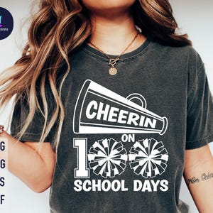 May include: A black t-shirt with a white graphic design of a megaphone with the text "Cheer On 100 School Days". The graphic also includes two white pom-poms.