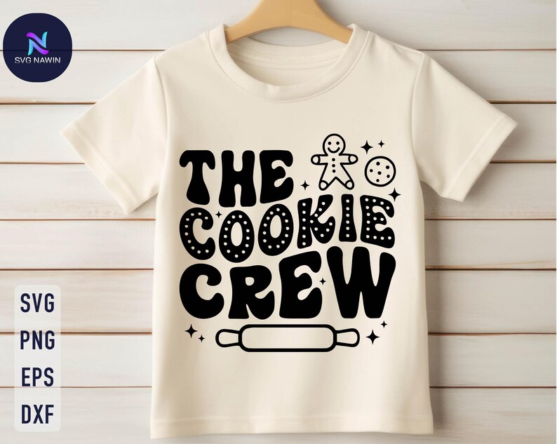 May include: White t-shirt with black text that reads "The Cookie Crew" and a gingerbread man graphic. There is also a rolling pin graphic and a cookie graphic.
