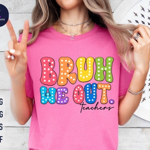 以下が含まれることがあります： 白のドット模様の虹色の文字で「Bruh We Out. Teachers」と書かれたピンクのTシャツです。