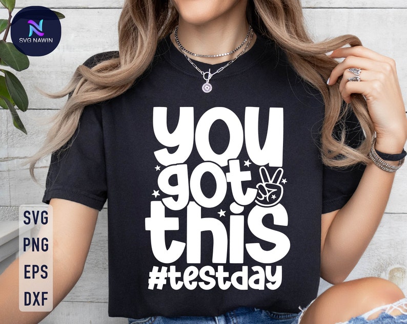 May include: Black t-shirt with white text that reads "You got this #testday" and a peace sign graphic.