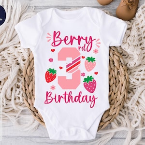 May include: White baby bodysuit with a pink strawberry design. The text "Berry 3rd Birthday" is printed on the front.