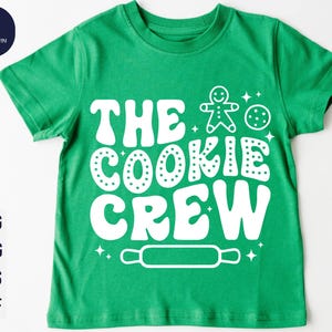 May include: Green t-shirt with white text that says "The Cookie Crew" and a gingerbread man and cookie graphic.