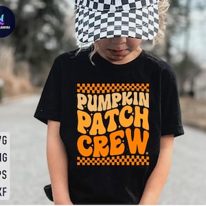 May include: A black t-shirt with an orange graphic that says "Pumpkin Patch Crew" in a retro font. The graphic is surrounded by a checkered border.