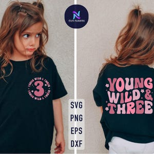以下が含まれることがあります： ピンクの文字で「Young Wild & Three」と書かれた黒いTシャツ。中央にはピンクの数字3が書かれている。子供用のTシャツです。