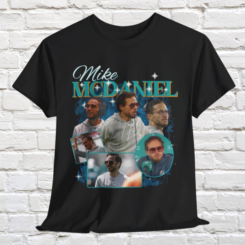 Puede incluir: Camiseta negra con un gr&aacute;fico de estilo vintage que presenta un collage de fotos de Mike McDaniel, el entrenador en jefe de los Miami Dolphins. El texto "Mike McDaniel" est&aacute; impreso en una fuente en negrita y estilizada.