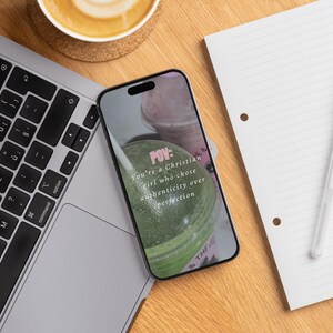 May include: A laptop, smartphone, coffee cup, notepad, and pen are arranged on a wooden surface. The smartphone displays text: "POV: You're a Christian girl who chose authenticity over perfection."